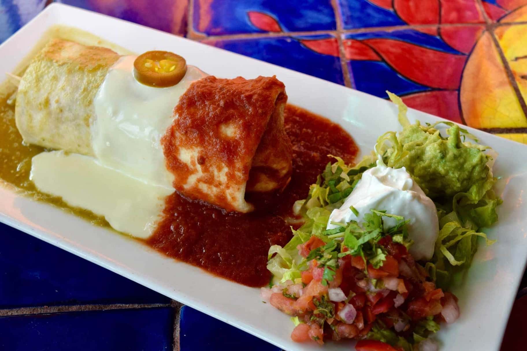 Stuffed burrito topped with sauce and cheese
