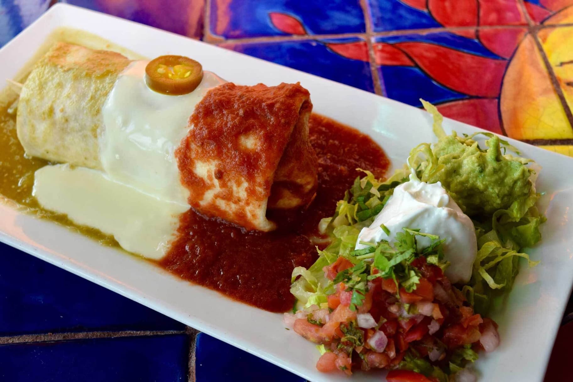 Stuffed burrito topped with sauce and cheese