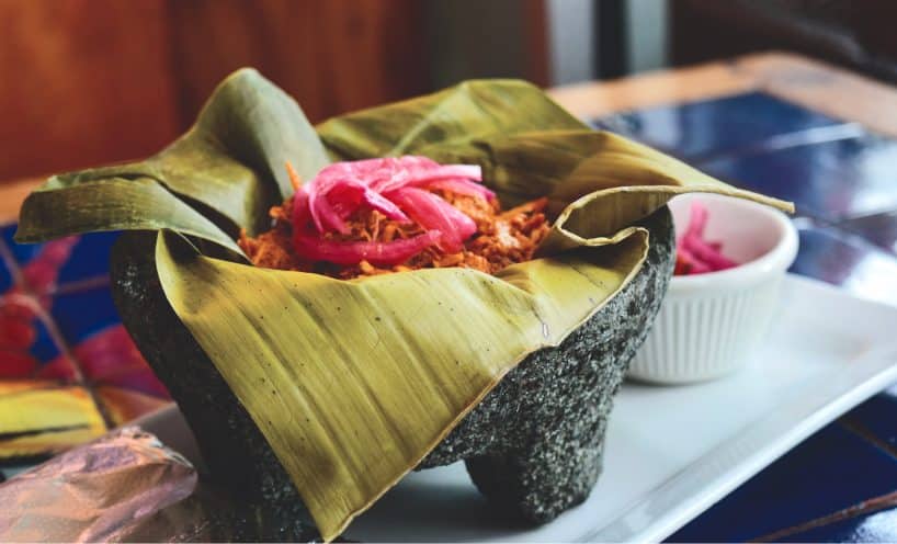 Cochinita pibil served in a banana leaf in a molcajete